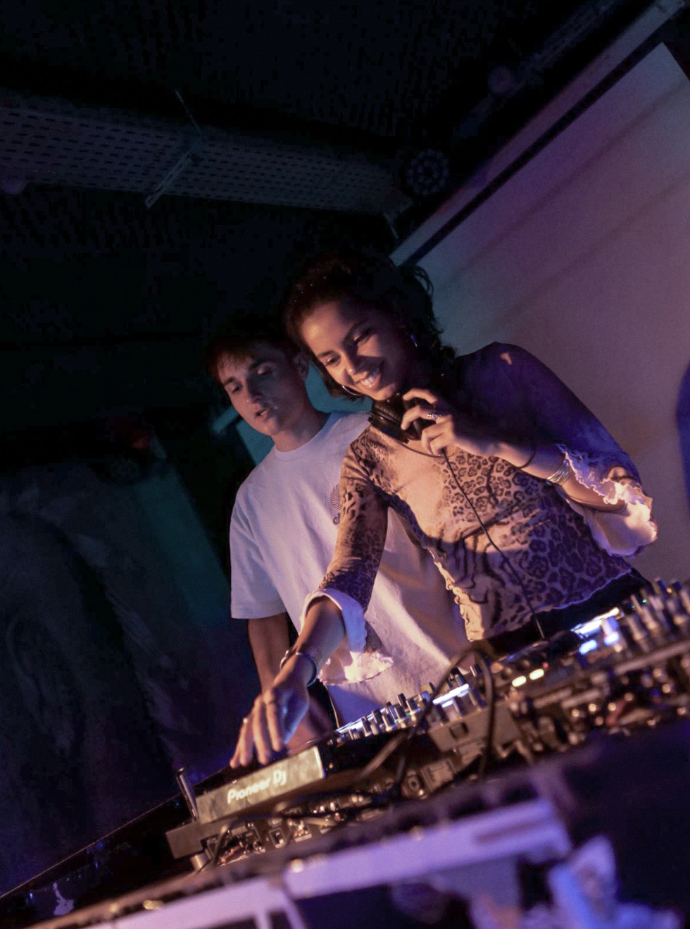 Une DJ sourit derrière les platines pendant une soirée.
