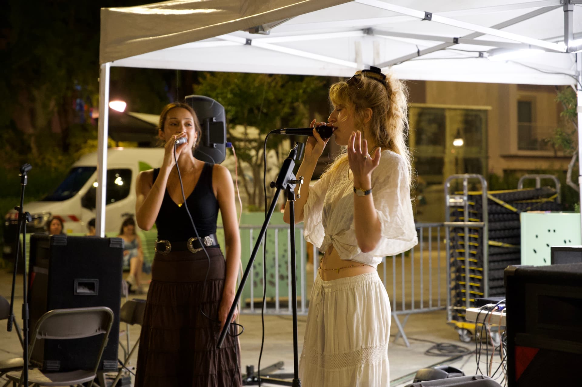 Deux chanteuses se produisent sous un chapiteau, de nuit.