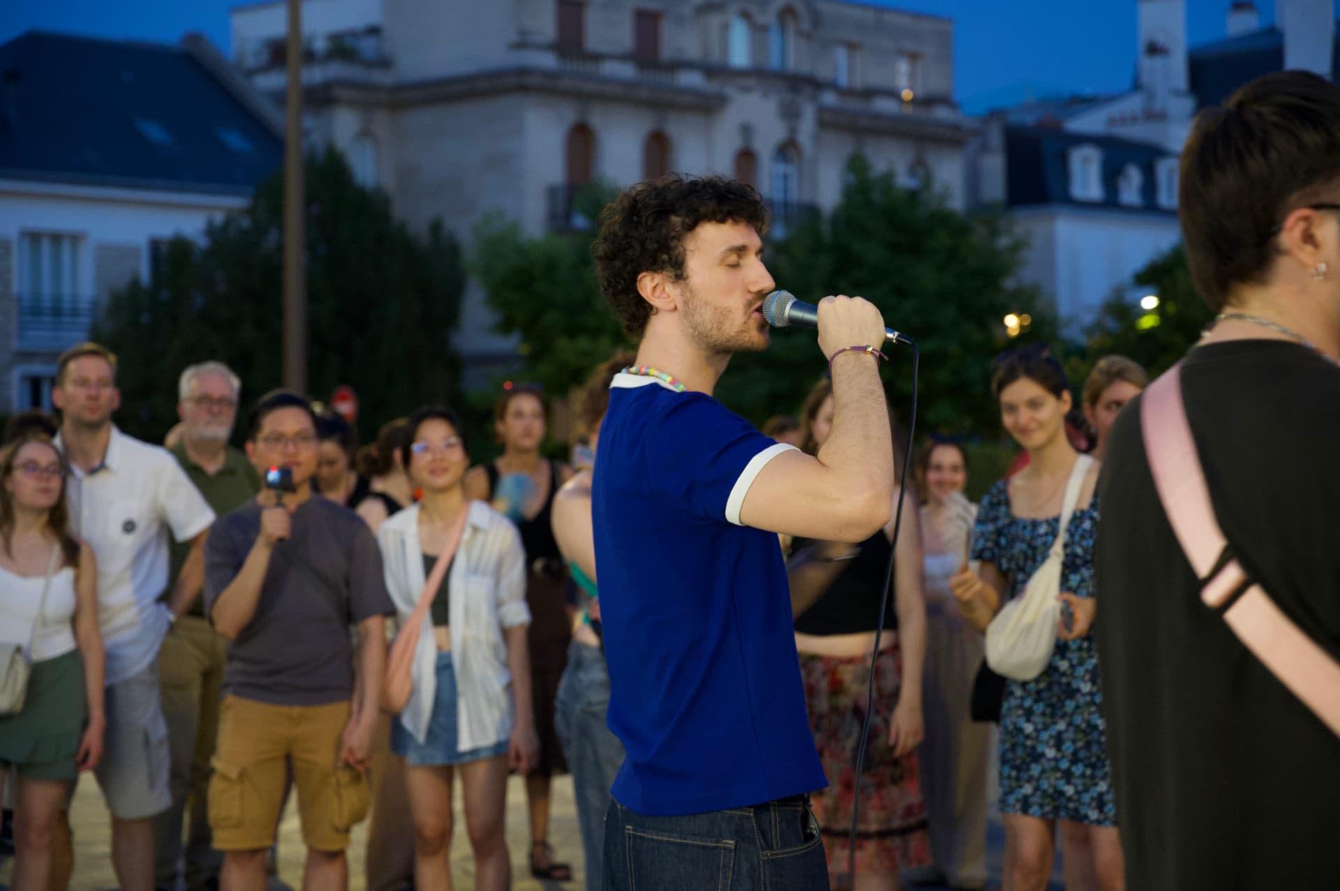 Un chanteur en plein concert en plein air, au crépuscule.
